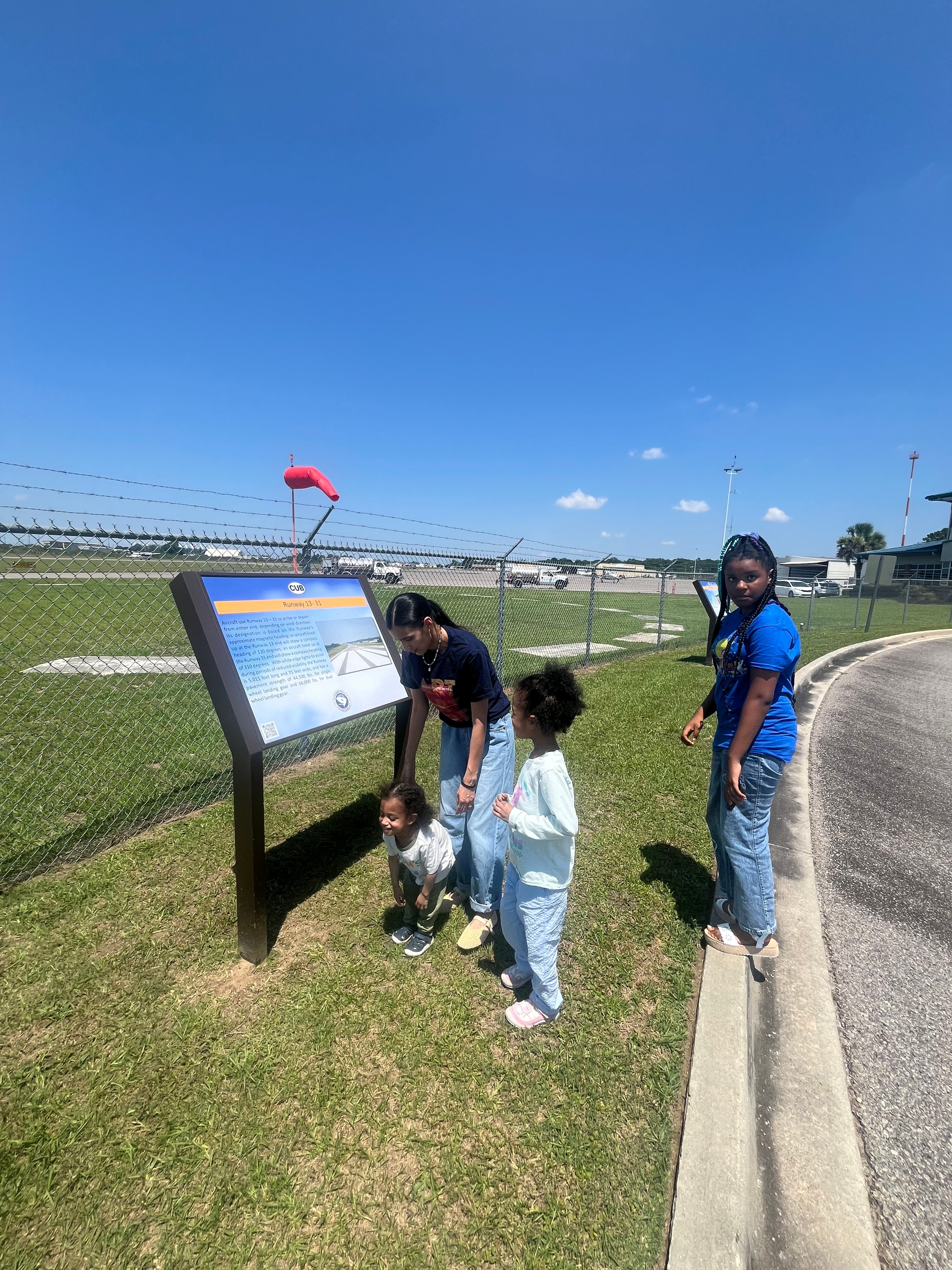 Aaliyah and co-op students reading an informational display on the airfield